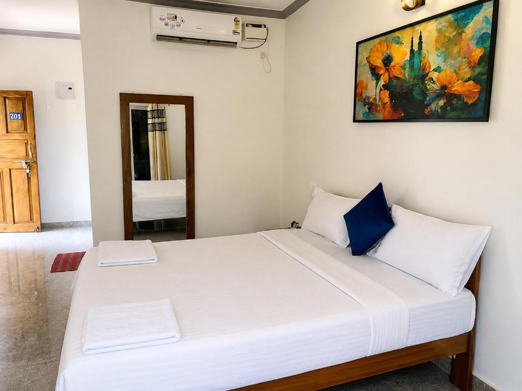 a bedroom with a white bed with a painting on the wall at Casa de Arambol in Arambol