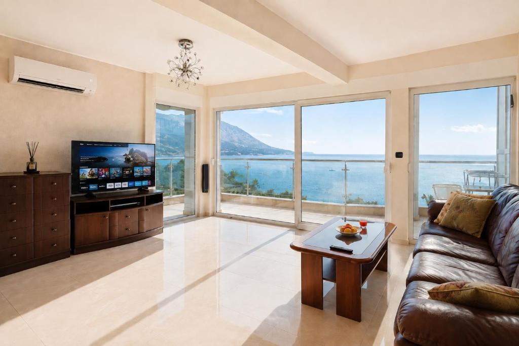 a living room with a couch and a tv and large windows at Penthouse Bečići Apartament in Bečići