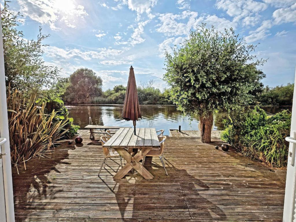 a table with an umbrella and a bench on a wooden dock at Dinky Daze - Ukc7071 in Brundall