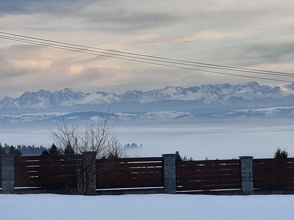 a fence with a view of snow covered mountains at Sielski domek w Orawce in Jabłonka