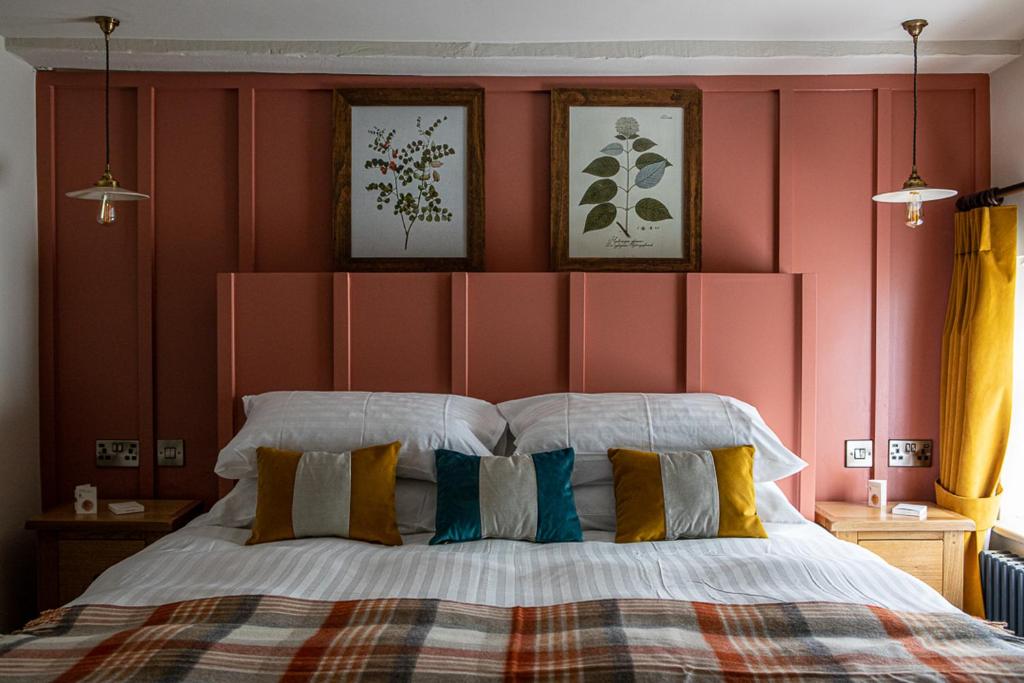 a bedroom with a large bed with a red wall at The Filly Inn in Brockenhurst