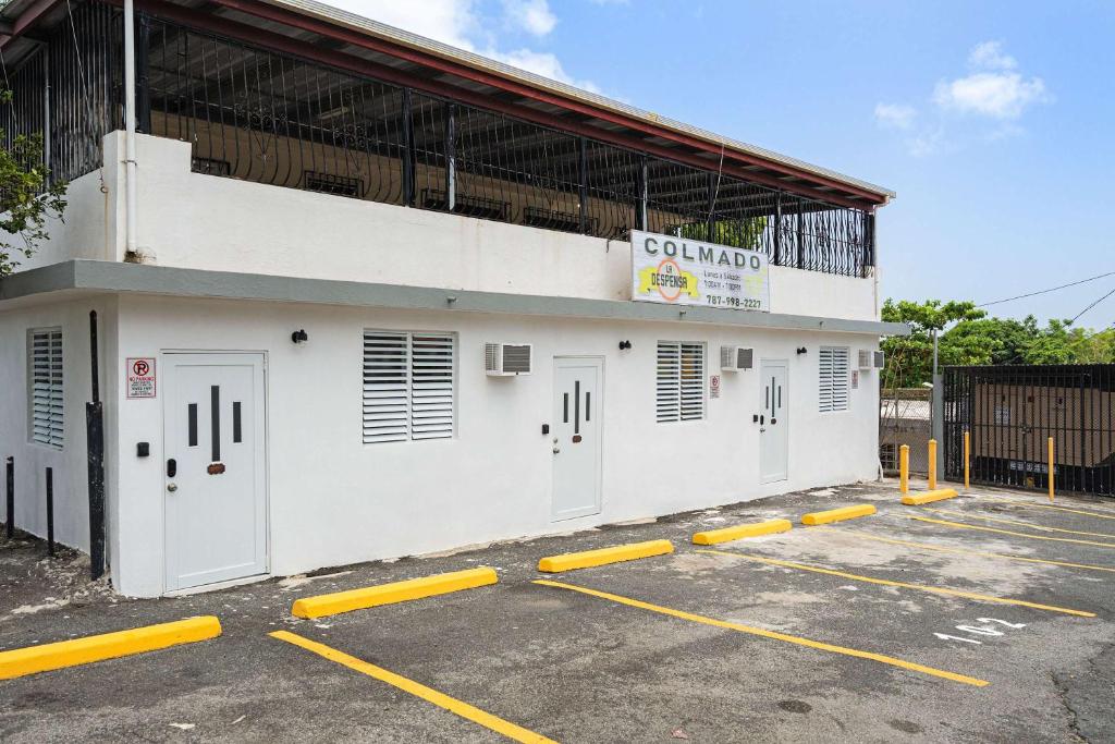 a white building with yellow parking spaces in a parking lot at Colmado by Otium in Hato Candal