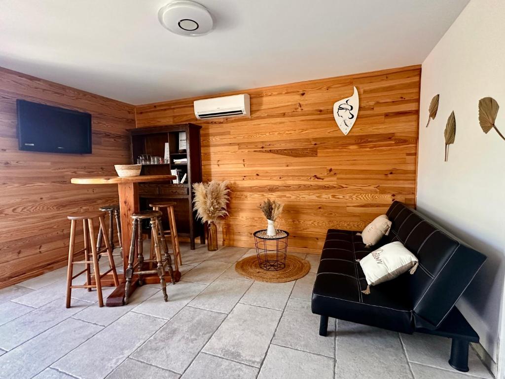 a living room with a black couch and wooden walls at Charmant chalet en montagne in Petreto-Bicchisano