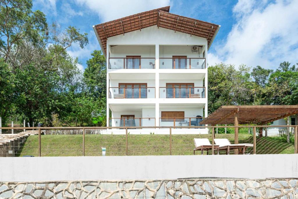 a white building with a fence in front of it at River & Ocean View House with Pool in Igarassu