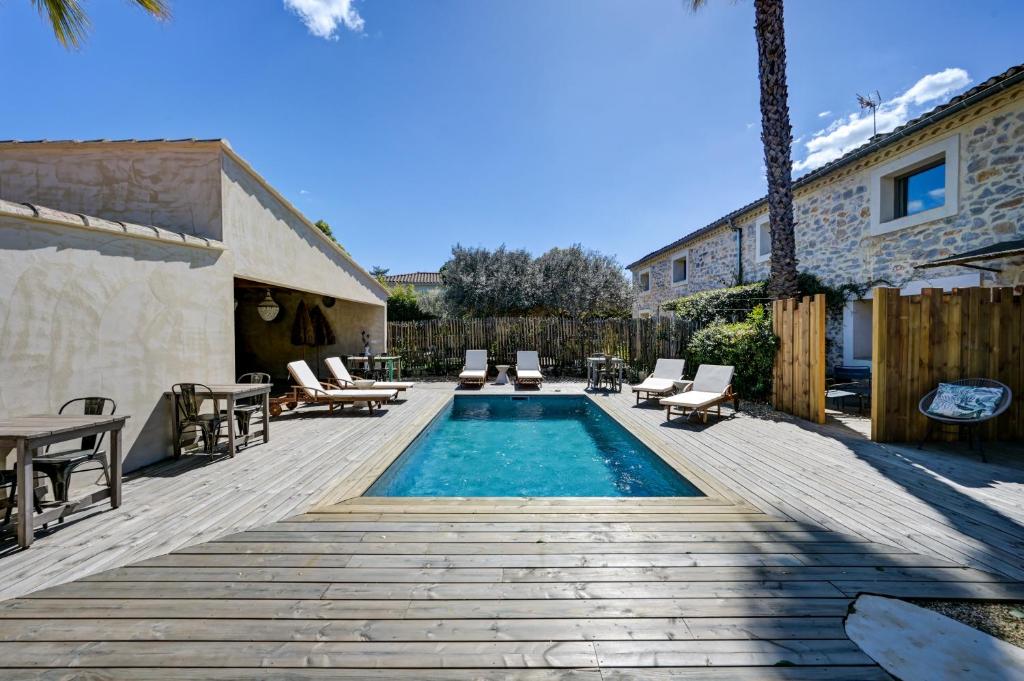 a backyard with a pool and chairs and a table at Le Mas Des Brunes in Saint-Laurent-dʼAigouze