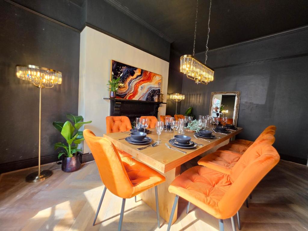 a dining room with a table and orange chairs at Fox House Llandudno in Llandudno