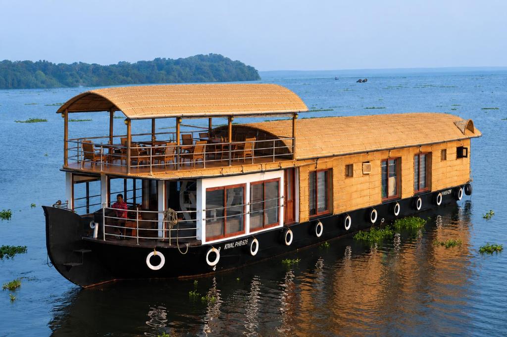 a house boat with a roof on the water at Kerala Boat Trips in Kumarakom