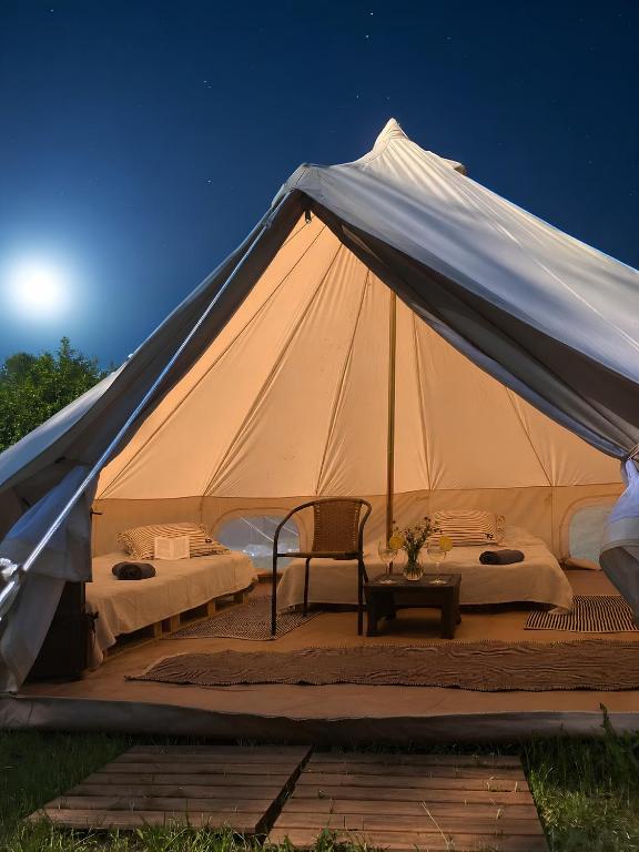 a large white tent with two beds and a chair at Mazury Glamping Kruklanki Polana Życzeń in Kruklanki