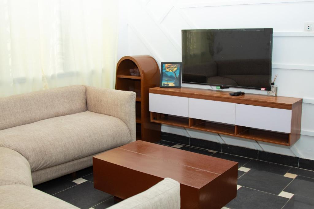 a living room with two chairs and a flat screen tv at Residences ACC in Abomey-Calavi