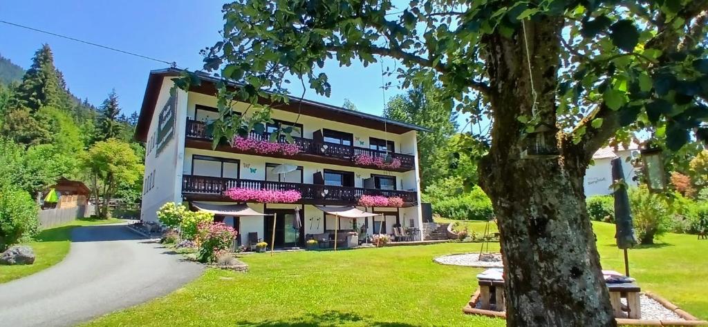 a large building with balconies and a tree at Pension & Apartments Weissbriach in Weissbriach
