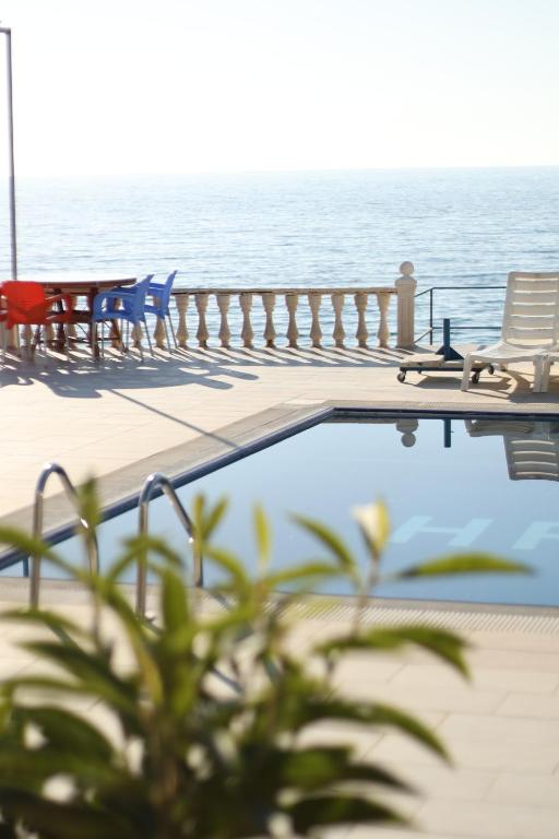 a swimming pool with chairs and tables next to the water at Hakan Pension in Merdivenlikuyu