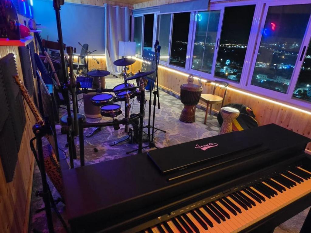 a piano in a room with a view of the city at Agadir Funky Chill , Surf & Music hostel in Aourir