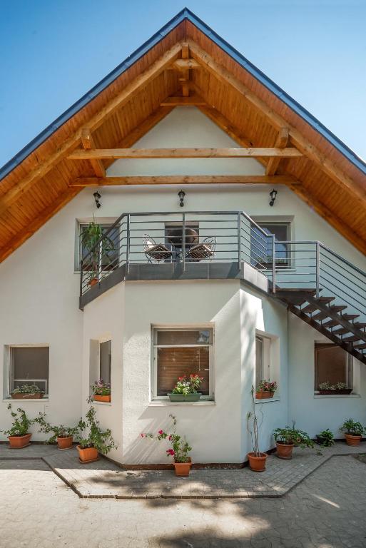 a white house with a balcony and potted plants at Rita Apartman in Balatonföldvár