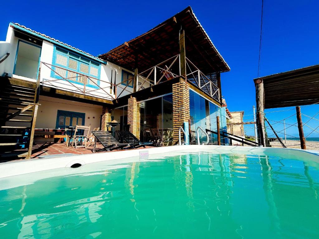 a house with a swimming pool in front of it at Pousada e restaurante casa dos ventos in Icapuí