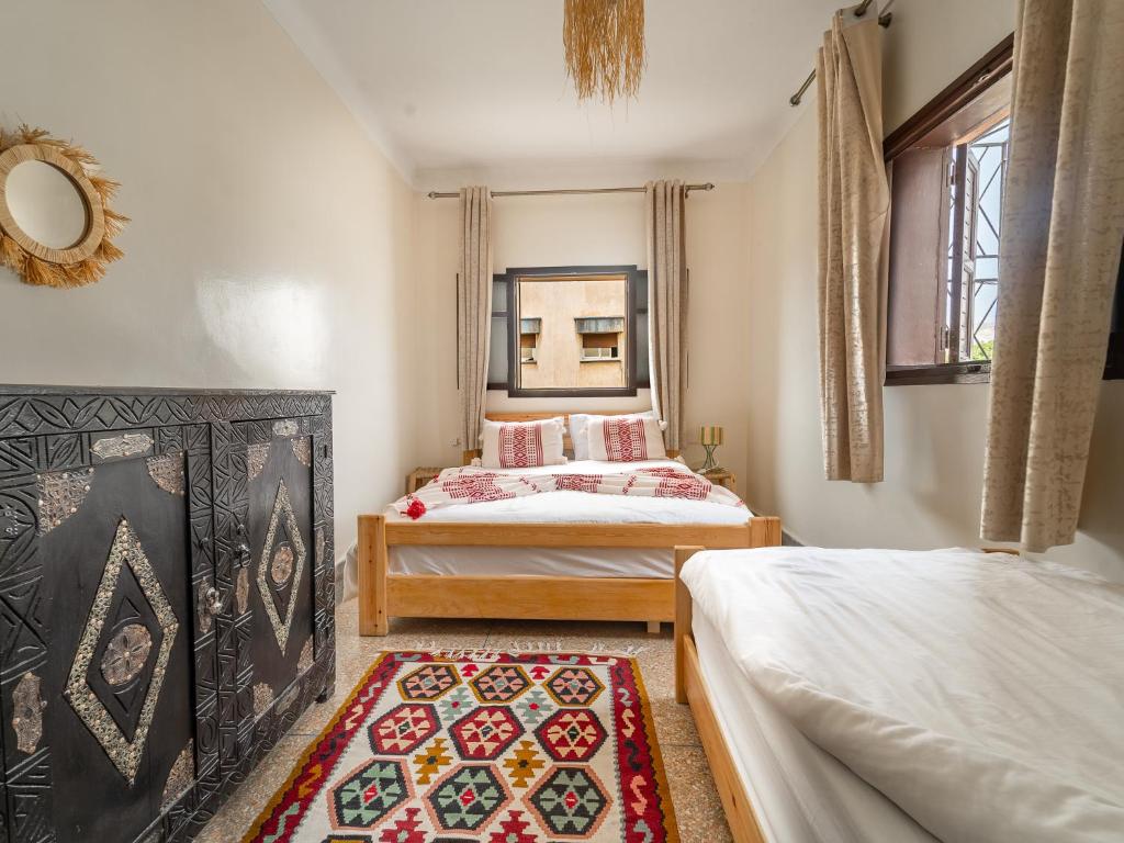 a bedroom with two beds and a rug on the floor at TAMOUNT Surf House in Agadir