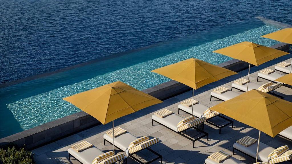 a group of chairs and umbrellas next to a pool at Gran Hotel Margalida by Annua Signature in Banyalbufar