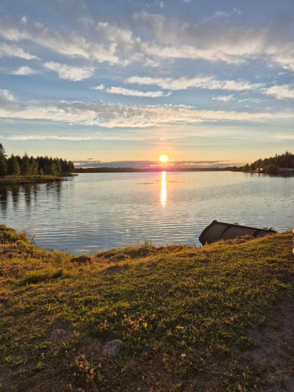 a sunset on a lake with a boat in the water at Koivutie Best rooms in Ranua