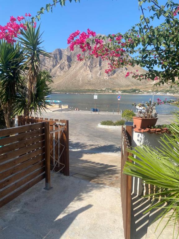 a wooden fence next to a beach with pink flowers at Villamare in Custonaci