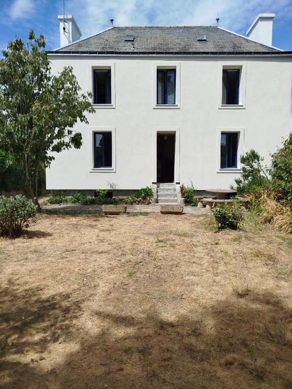 a large white house with a yard in front of it at Les lilas in Moëlan-sur-Mer