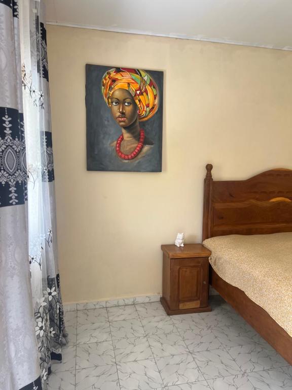 a bedroom with a painting of a woman on the wall at Georgianas Residence in Kartung