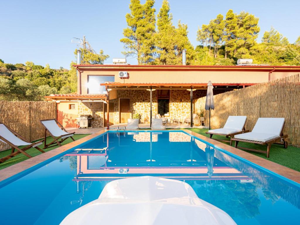 a swimming pool with chairs and a house at Green Olive Luxury Villas in Paliouri