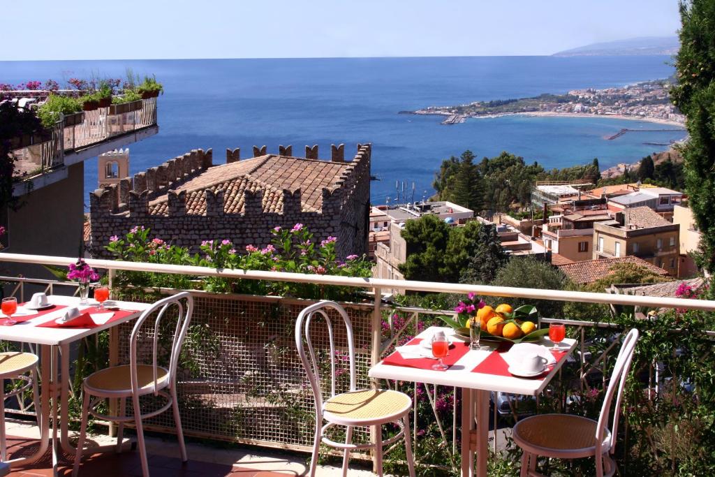a balcony with tables and chairs and a view of the ocean at Hotel Mediterranée in Taormina