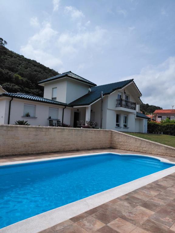 a villa with a swimming pool in front of a house at Tejas verdes in Argoños