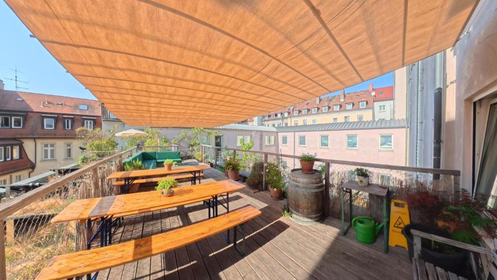 a deck with wooden tables and benches on a balcony at Babelfish Hostel in Würzburg