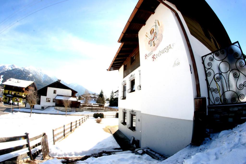 ein Gebäude mit Schnee auf dem Boden neben einem Zaun in der Unterkunft Family Friendly Chalet - Central with Beautiful Mountain Views in Seefeld in Tirol