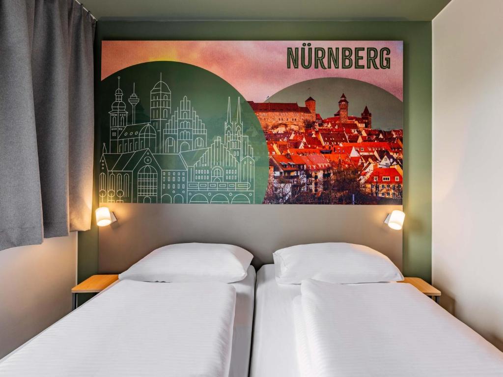 two beds in a room with a poster on the wall at B&B Hotel Nürnberg-City in Nuremberg