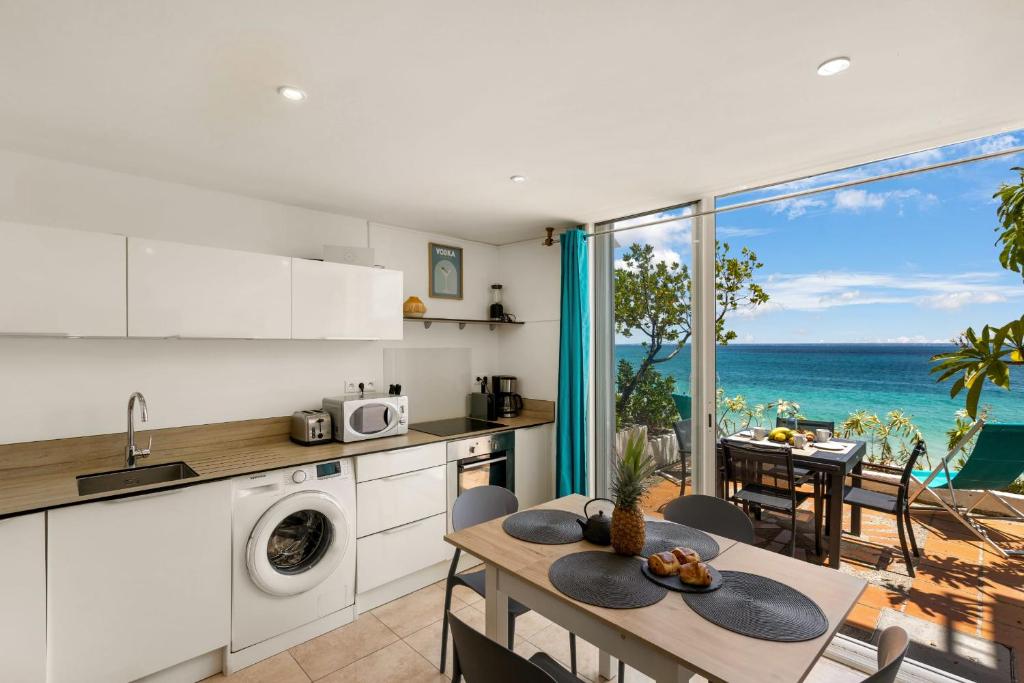 a kitchen and dining room with a view of the ocean at Watalibi - Beachfront apartment Grand-Case in Grand Case