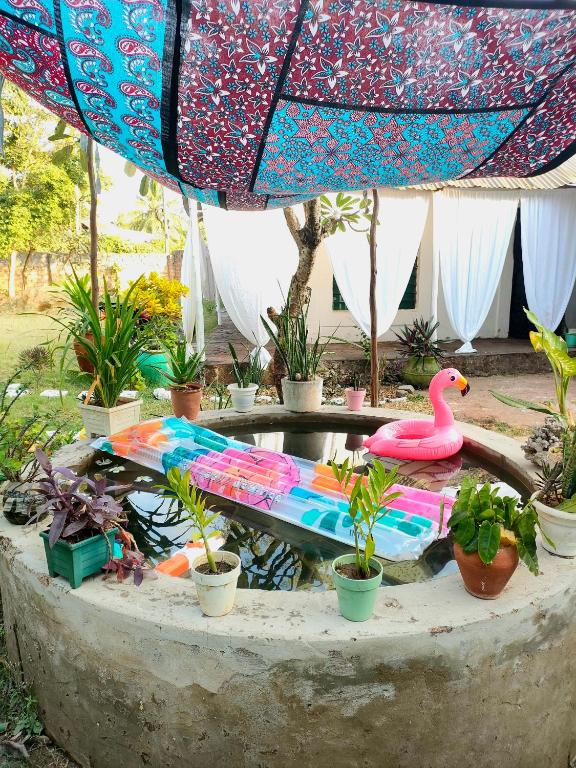 a bird bath with a pink flamingo and potted plants at Palm Paradise in Diani Beach