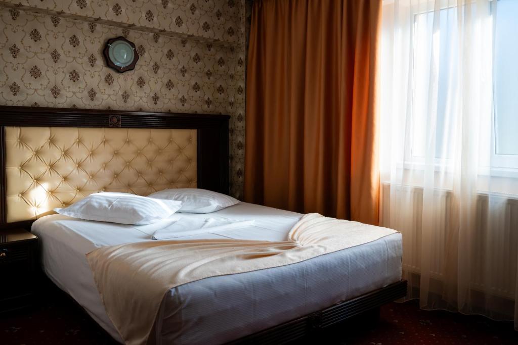 a bedroom with a large bed with a window at Pensiunea ORIENT in Brăila