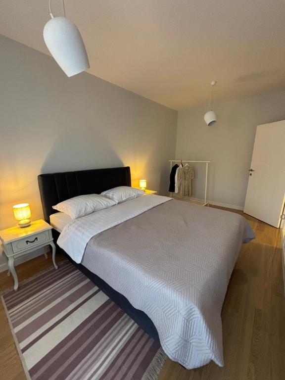 a bedroom with a large white bed with a striped rug at Apartman Vila&Vera in Sremska Mitrovica