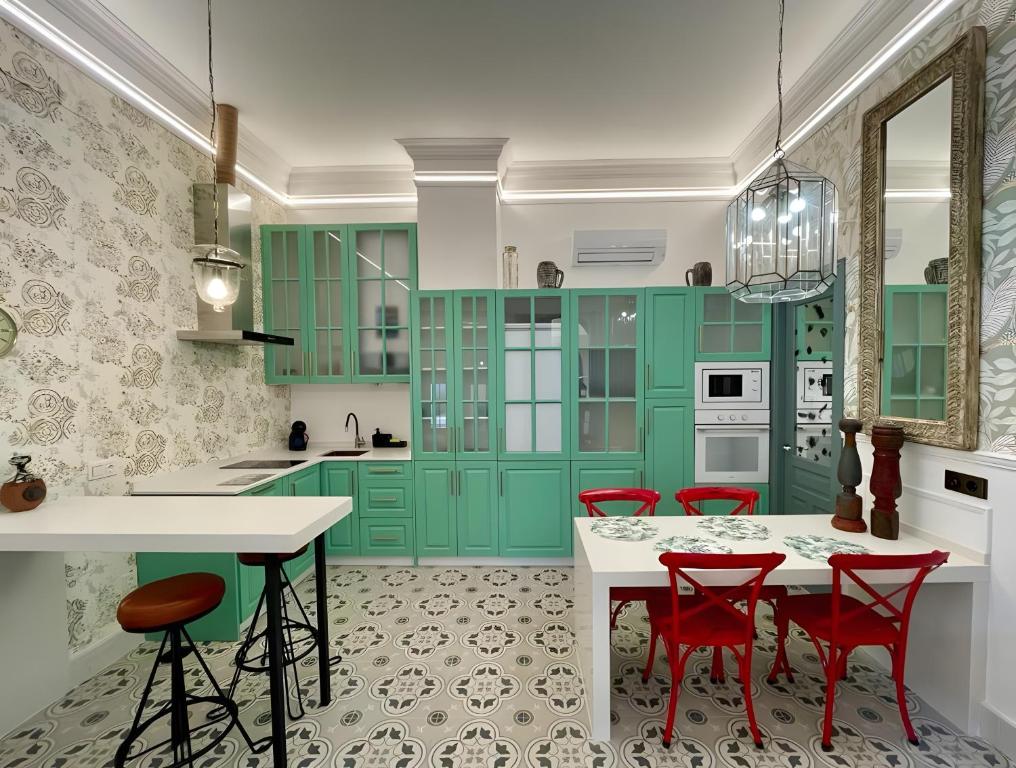 a kitchen with green cabinets and red chairs at Apartamento El Mar Azul 5 in Torremolinos