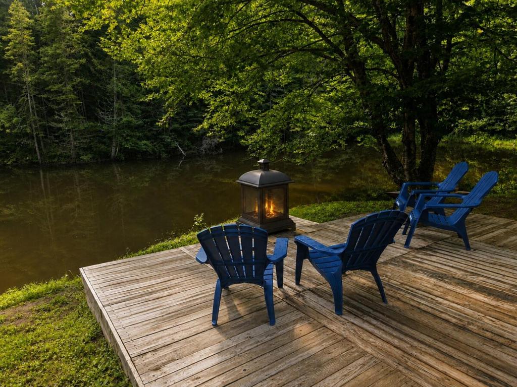 three blue chairs and a lantern on a wooden dock at Chalet avec spa et lac privé in Saint Come