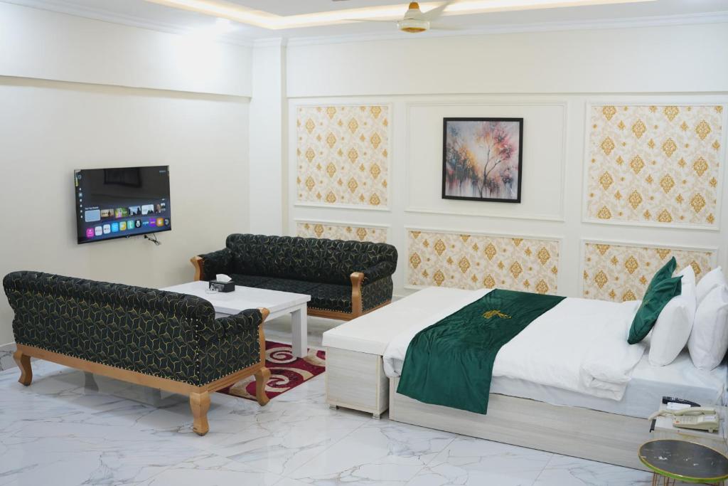 a bedroom with a bed and chairs and a tv at Pc Inn Executive Class Hotel in Sukkur