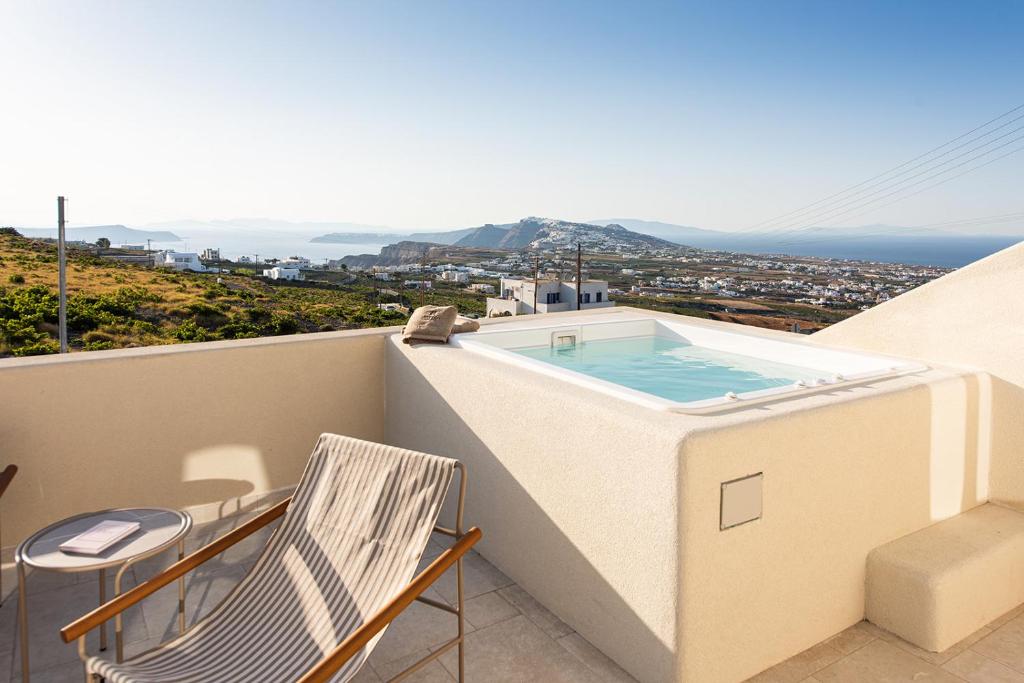 a balcony with a swimming pool and a chair at Avento Luxury Suites in Santorini