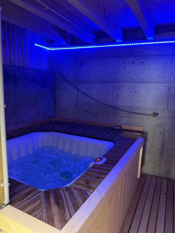 a jacuzzi tub in a room with blue lights at Gite de groupe lacs et forêt du jura - SPA et Sauna Privatif - Orgelet in Orgelet