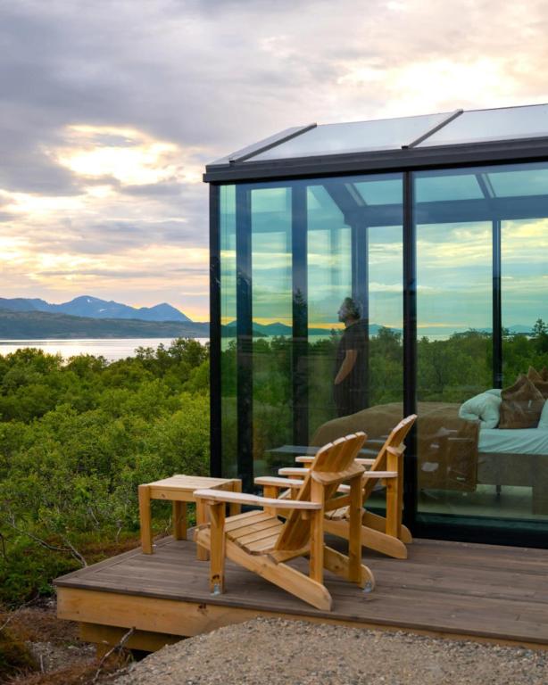 a glass house with a person taking a picture of the water at WonderInn Arctic in Utstrand