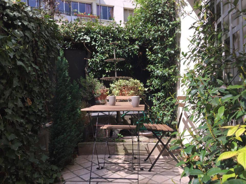 a table and chairs in a garden with plants at 1 Square du Docteur Blanche - Paris 16 in Paris