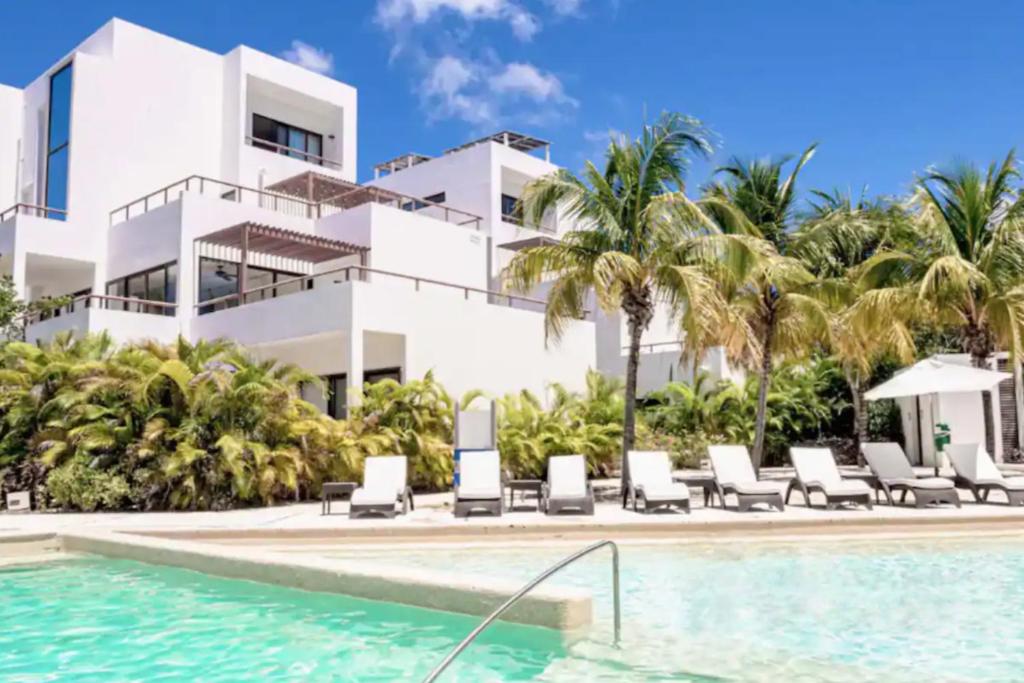 a resort with a swimming pool and palm trees at Bright 1 BD with private Terrace near TULUM in Akumal