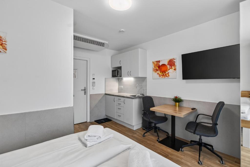 a bedroom with a bed and a table and a kitchen at AJO Apartments - Vetmed - Self-Check-in in Vienna