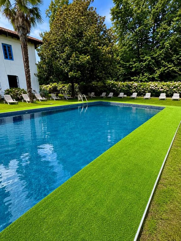 a swimming pool with green grass and chairs in a yard at Hotel Termas de Liérganes in Liérganes