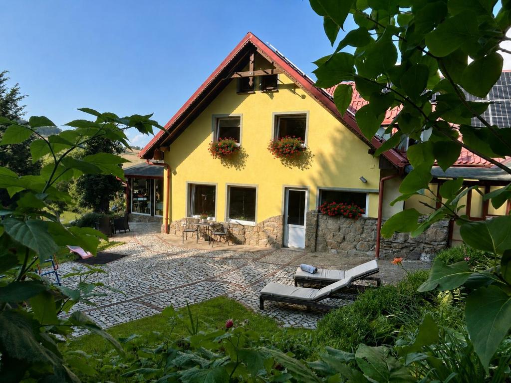 a yellow house with a bench in front of it at Gościniec Saba in Zieleniec