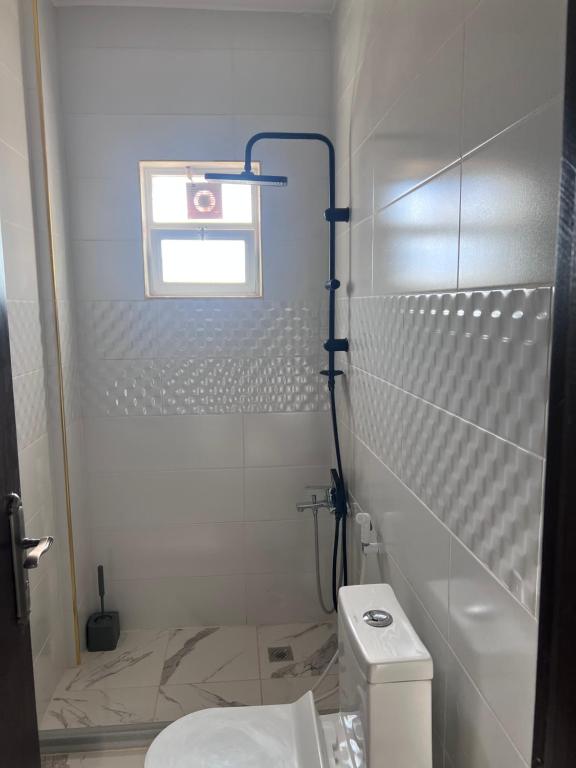 a white bathroom with a toilet and a window at Ali Building in Wadi Musa