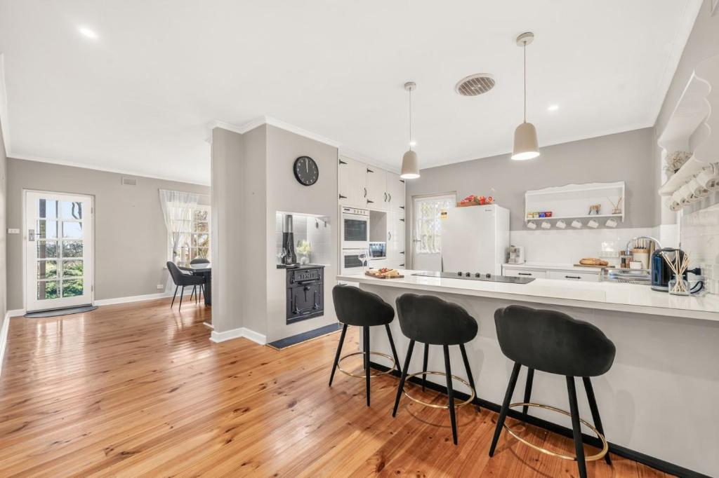 a kitchen and dining room with white appliances and black stools at The Retreat, Barossa Valley in Lights Pass