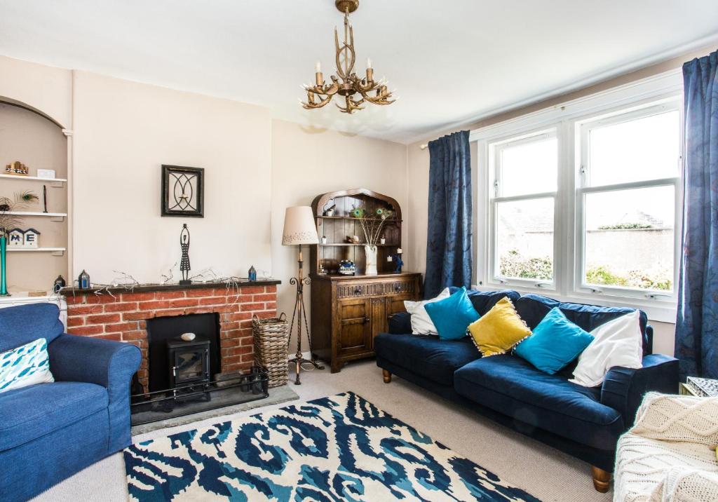 a living room with blue couches and a fireplace at Lynn Cottage in East Linton