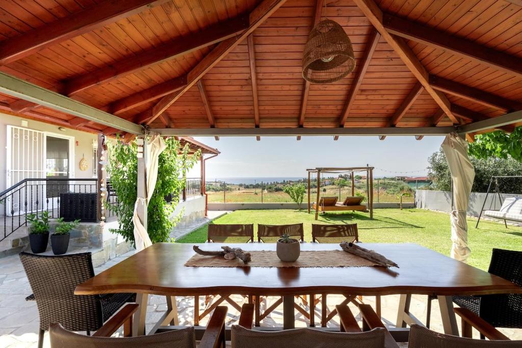 a patio with a table and chairs and a swing at Sunset Luxury Potidea in Metókhion Patriotikón