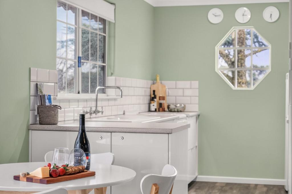 a white kitchen with a table and a sink at Grace Cottage, Barossa Valley in Lights Pass